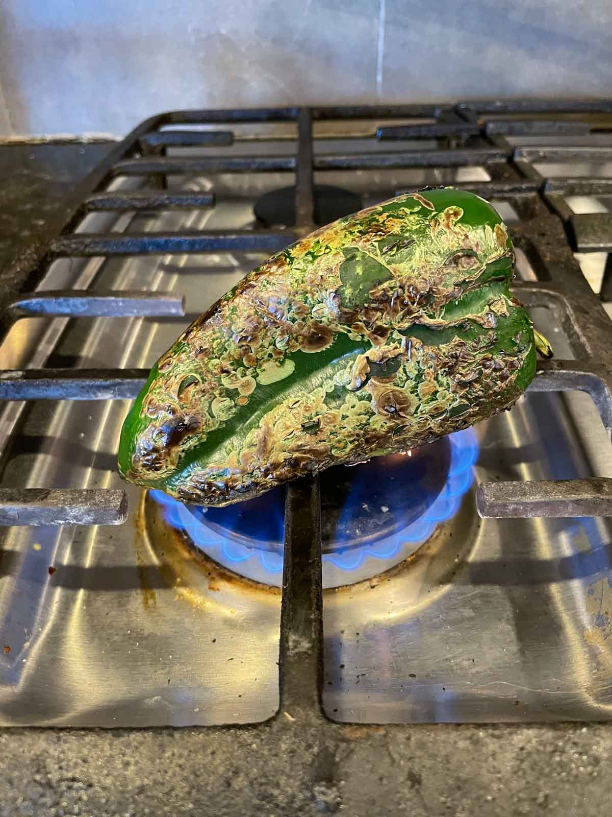 Roasting a poblano pepper on a gas stovetop.