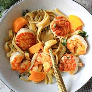 A bowl of shrimp scallop pasta with orange cream sauce.
