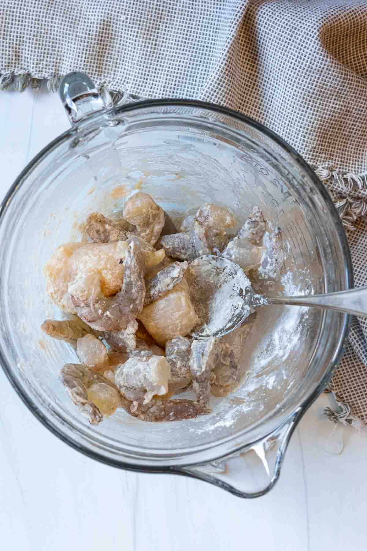 Coating shrimp and scallops with flour to make shrimp scallop pasta.