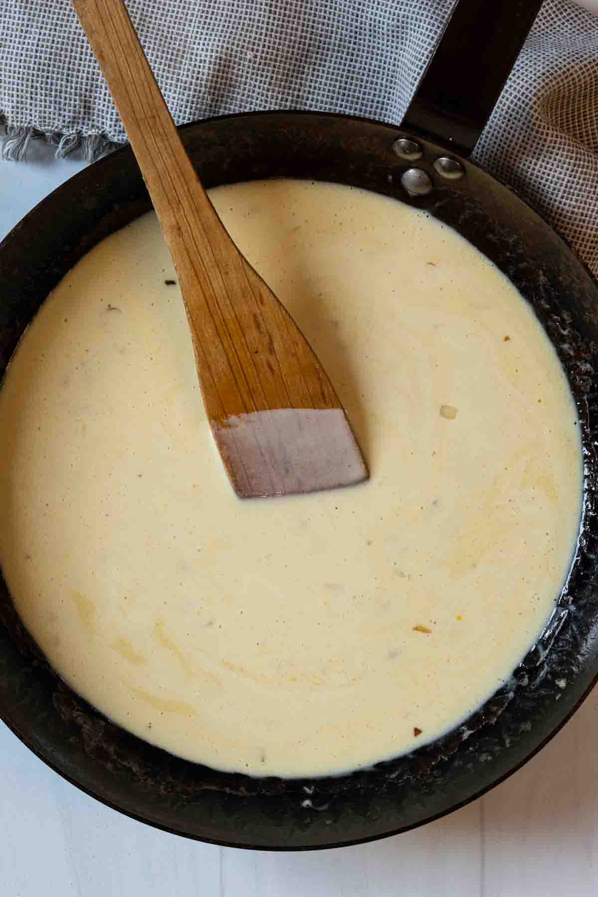 Adding cream to sauce ingredients to make shrimp scallop pasta.