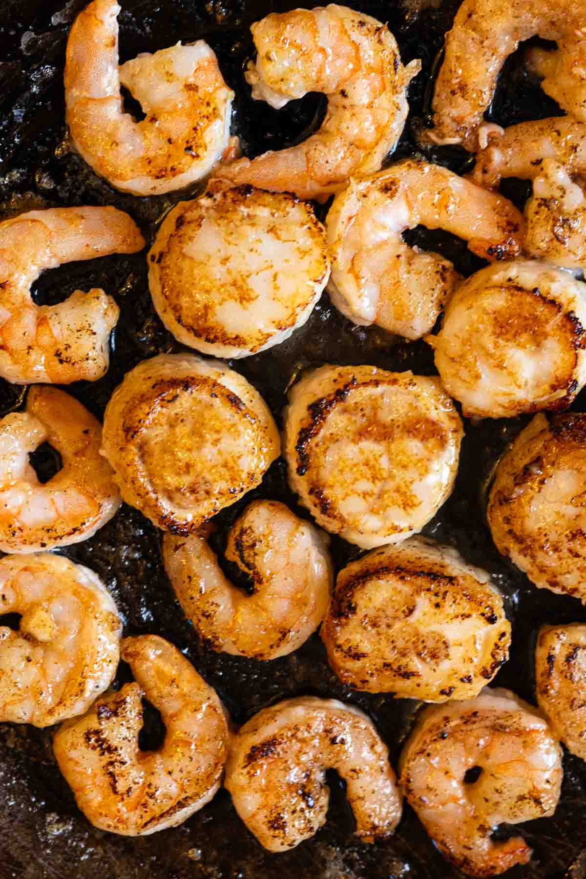 Frying shrimp and scallops to make shrimp scallop pasta.