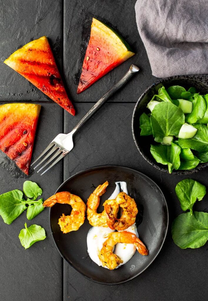 Grilled watermelon wedges with curried shrimp on greek yogurt with a watercress salad