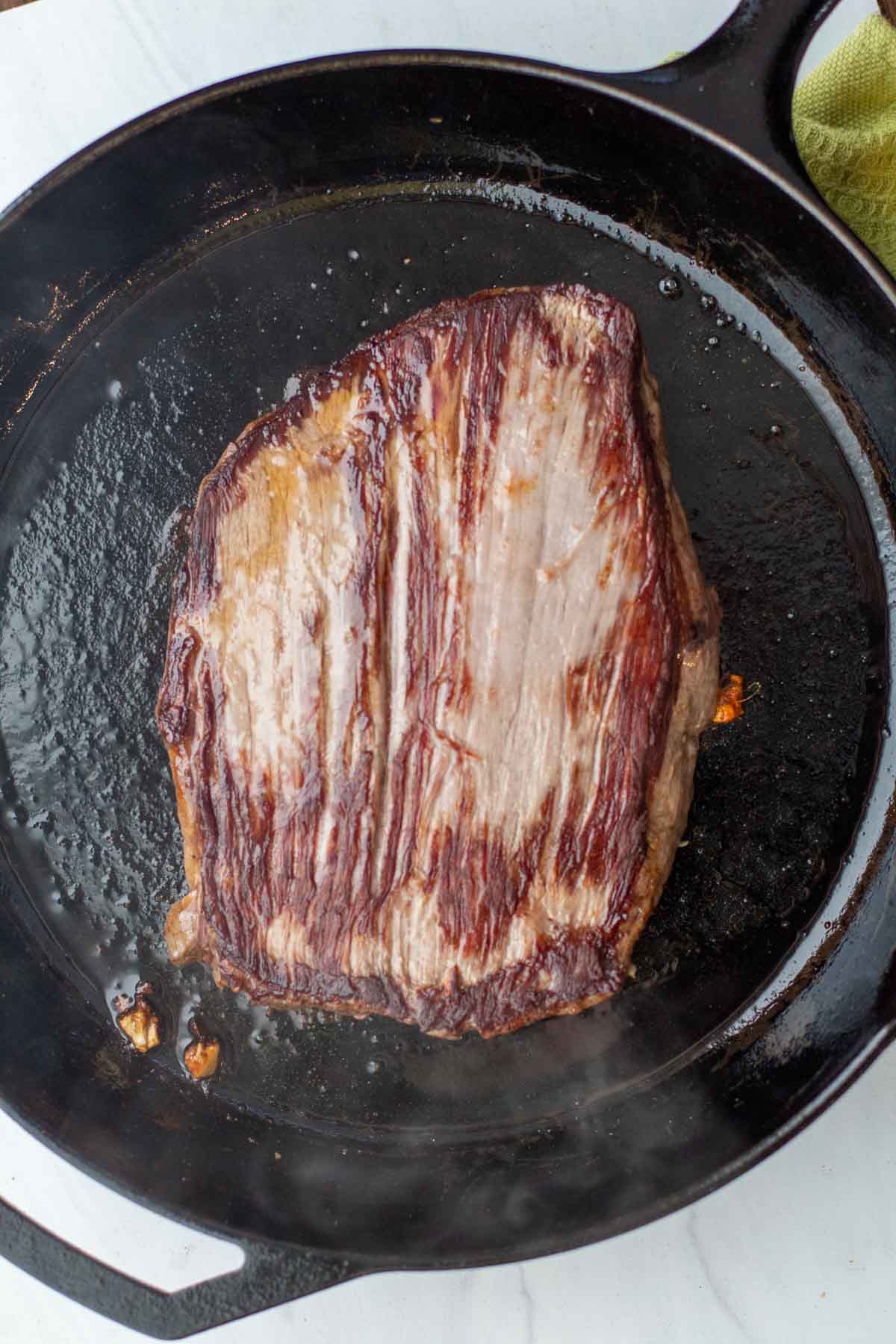 Cooking a flank steak in a cast iron skillet.