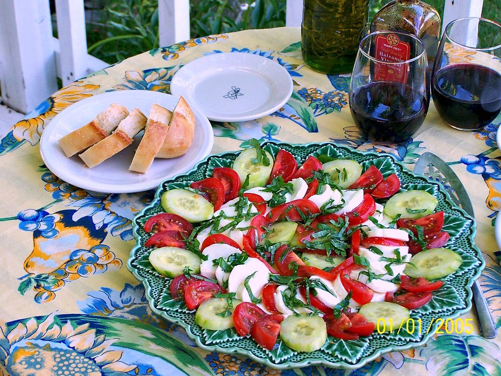 Caprese Salad. A summer salad of fresh mozzarella, fresh home grown tomatoes and english cucumber. Topped with fresh basil leaves.