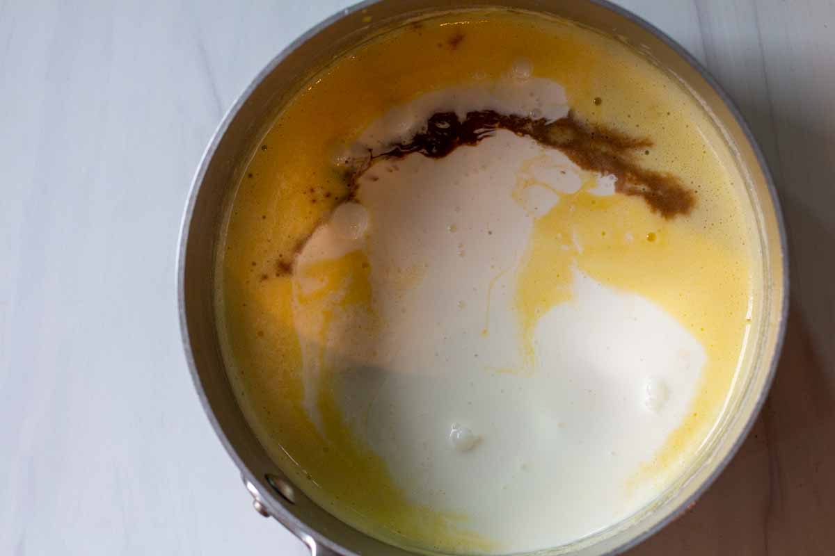 Adding vanilla and cream to milk egg mixture to make peach ice cream.