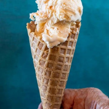 Homemade peach ice cream in a waffle cone.