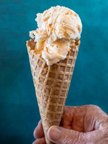Homemade peach ice cream in a waffle cone.