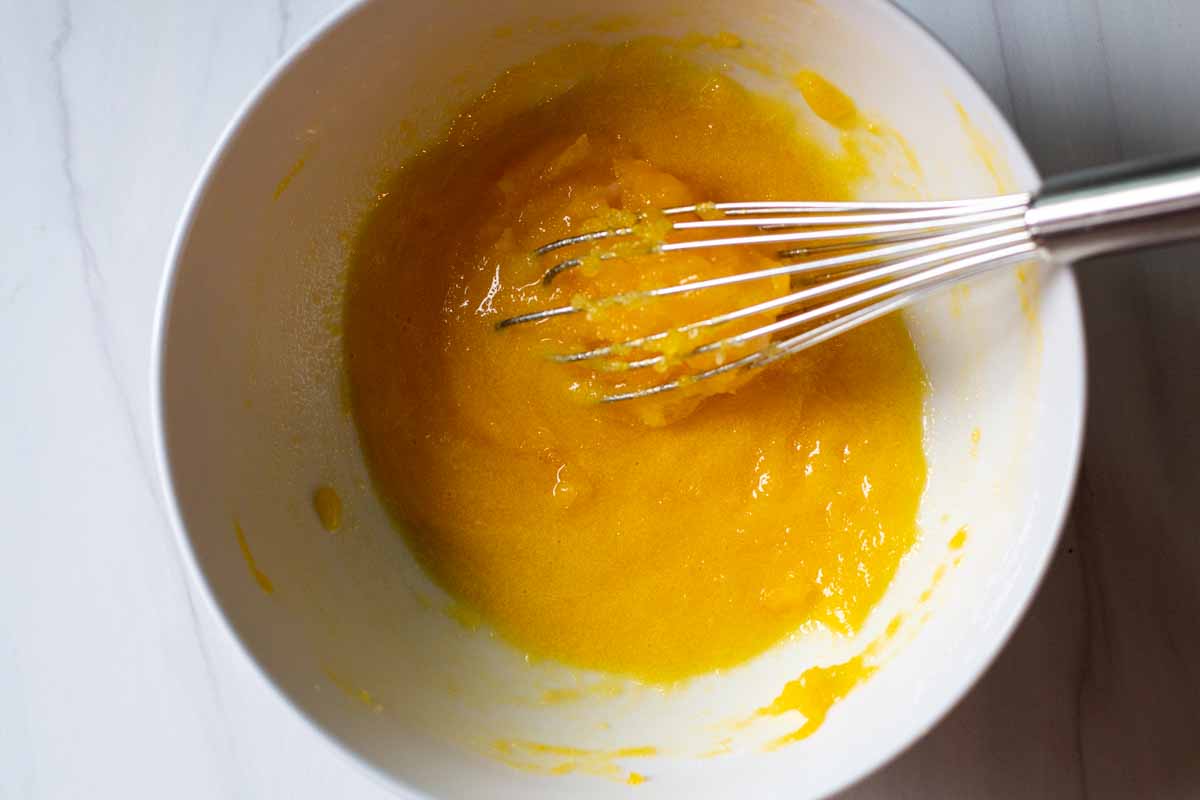Whisking sugar and egg yolks together to make homemade peach ice cream.