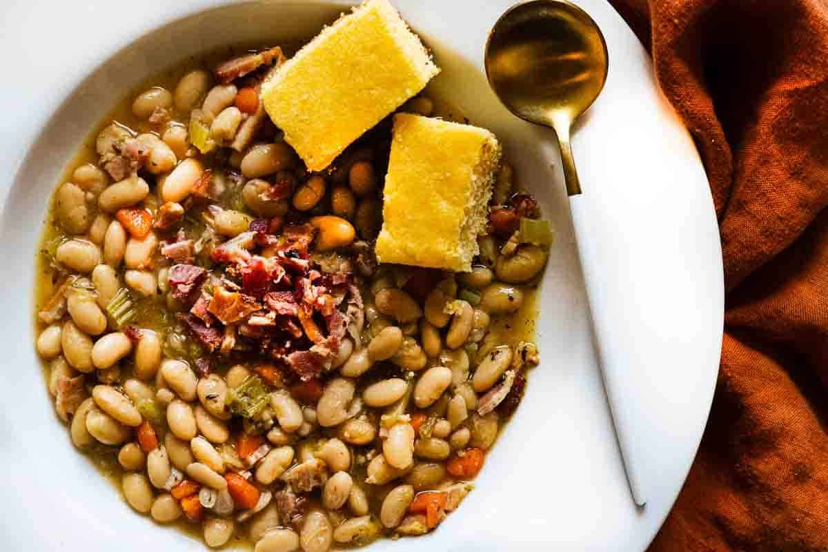 Great northern bean soup topped with bacon bits and two slices of cornbread.