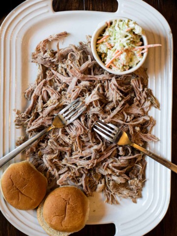 A platter of pulled pork with cole slaw and buns