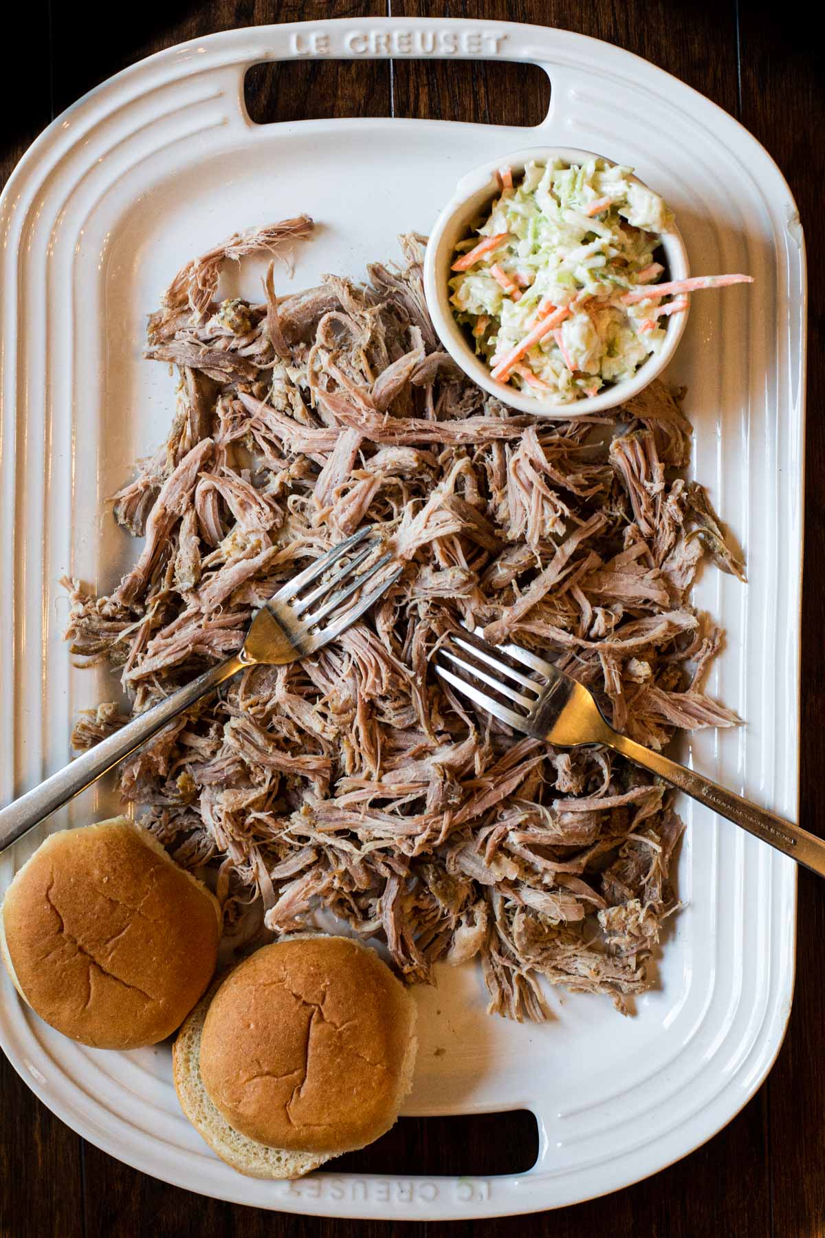 A platter of pulled pork with cole slaw and buns