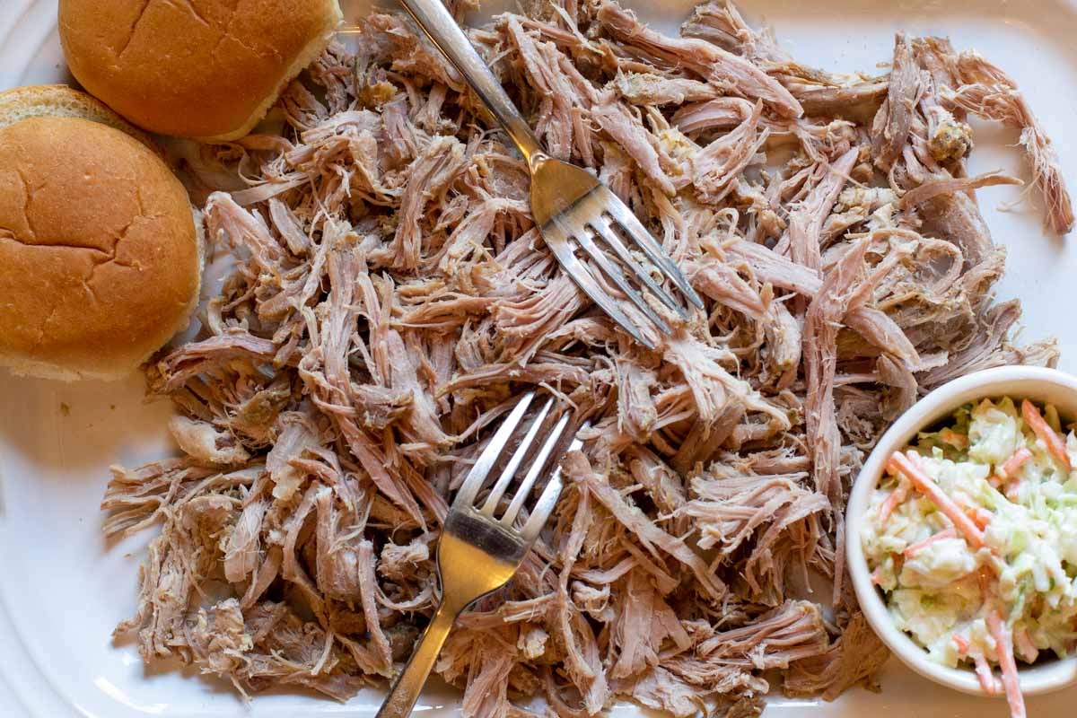 Using forks to shred pulled pork roast for pulled pork sandwiches