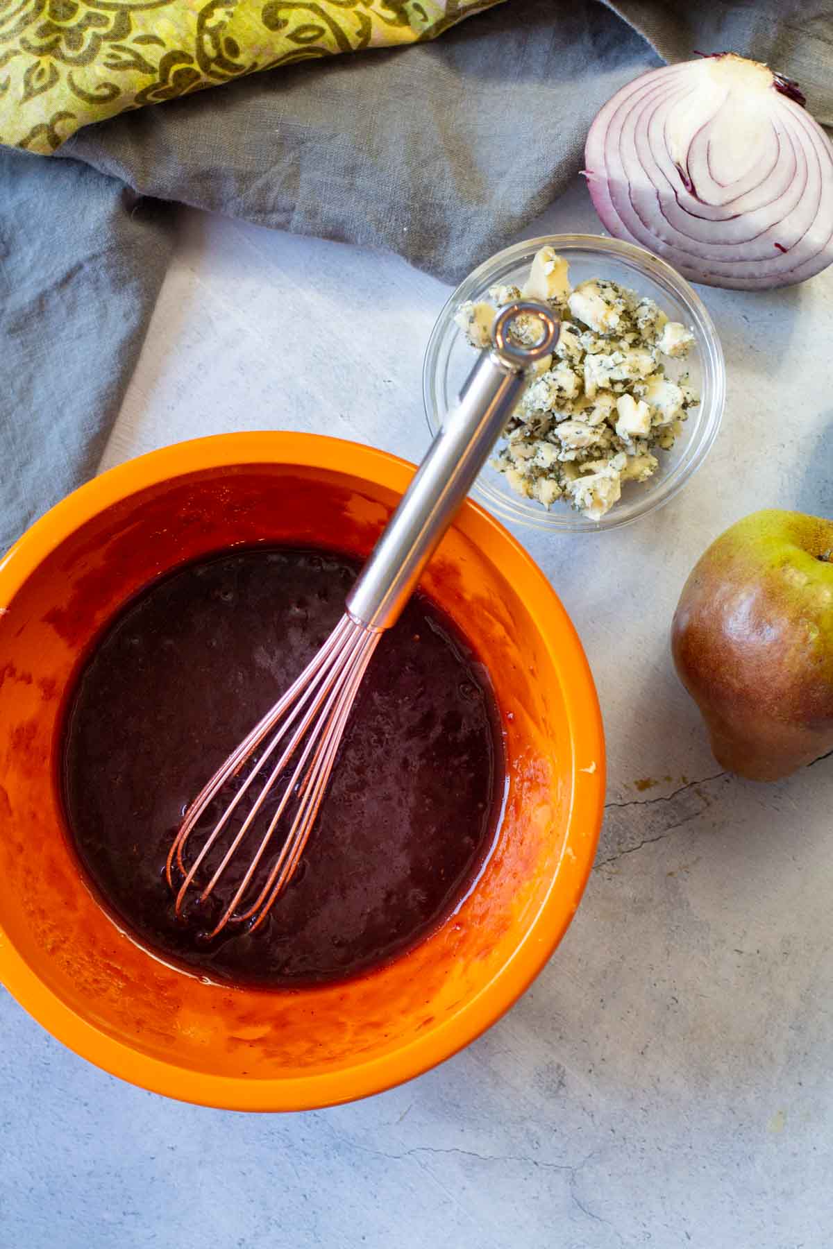 Using a whisk to blend ingredients together to make cranberry vinaigrette.