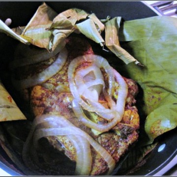 Achiote Paste Shredded Pork Tacos wrapped in banana leaves and topped with onions.
