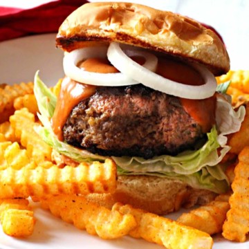 bison burger topped with sauce and onion rings, served with fries