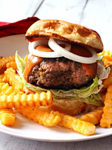 bison burger topped with sauce and onion rings, served with fries