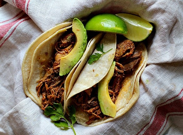 Achiote shredded pork tacos with avocado served in soft corn tortillas garnished with cilantro leaves