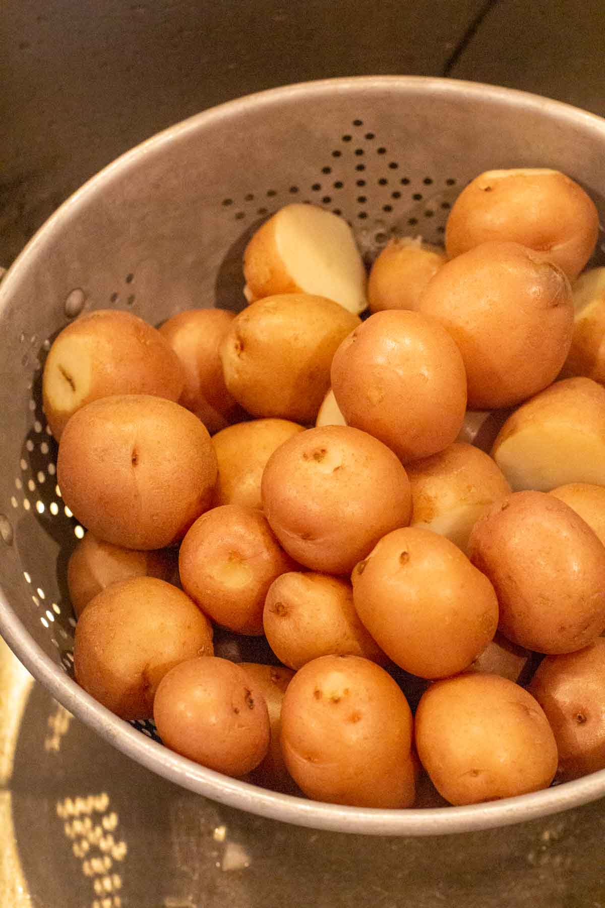 Draining cooked red potatoes to make classic potato salad.
