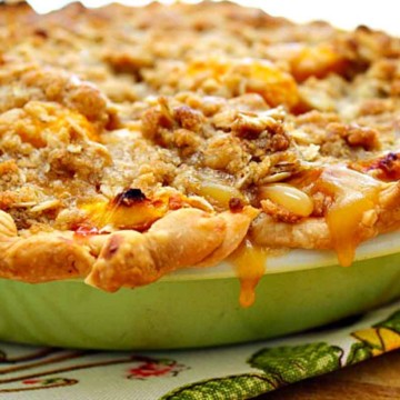 Peach crumble pie in an antique green Pyrex pie pan.