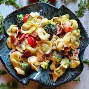 Cheese tortellini pasta salad served in a blue bowl.