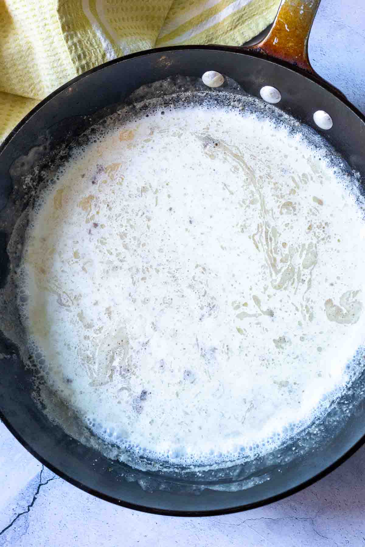Adding milk to roux in fry pan to make fried chicken gravy.