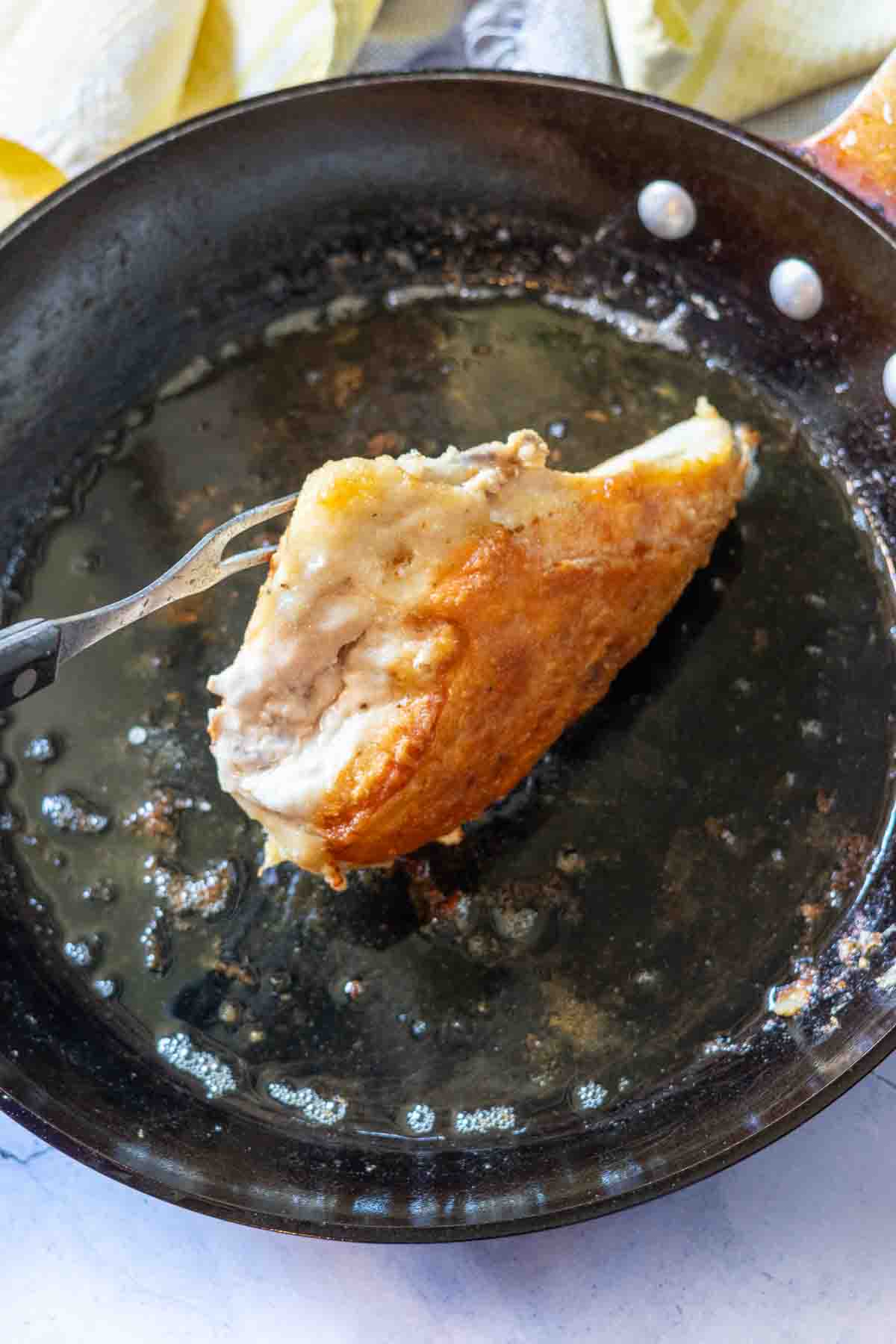 Cooking chicken breasts on all sides to make pan fried chicken.