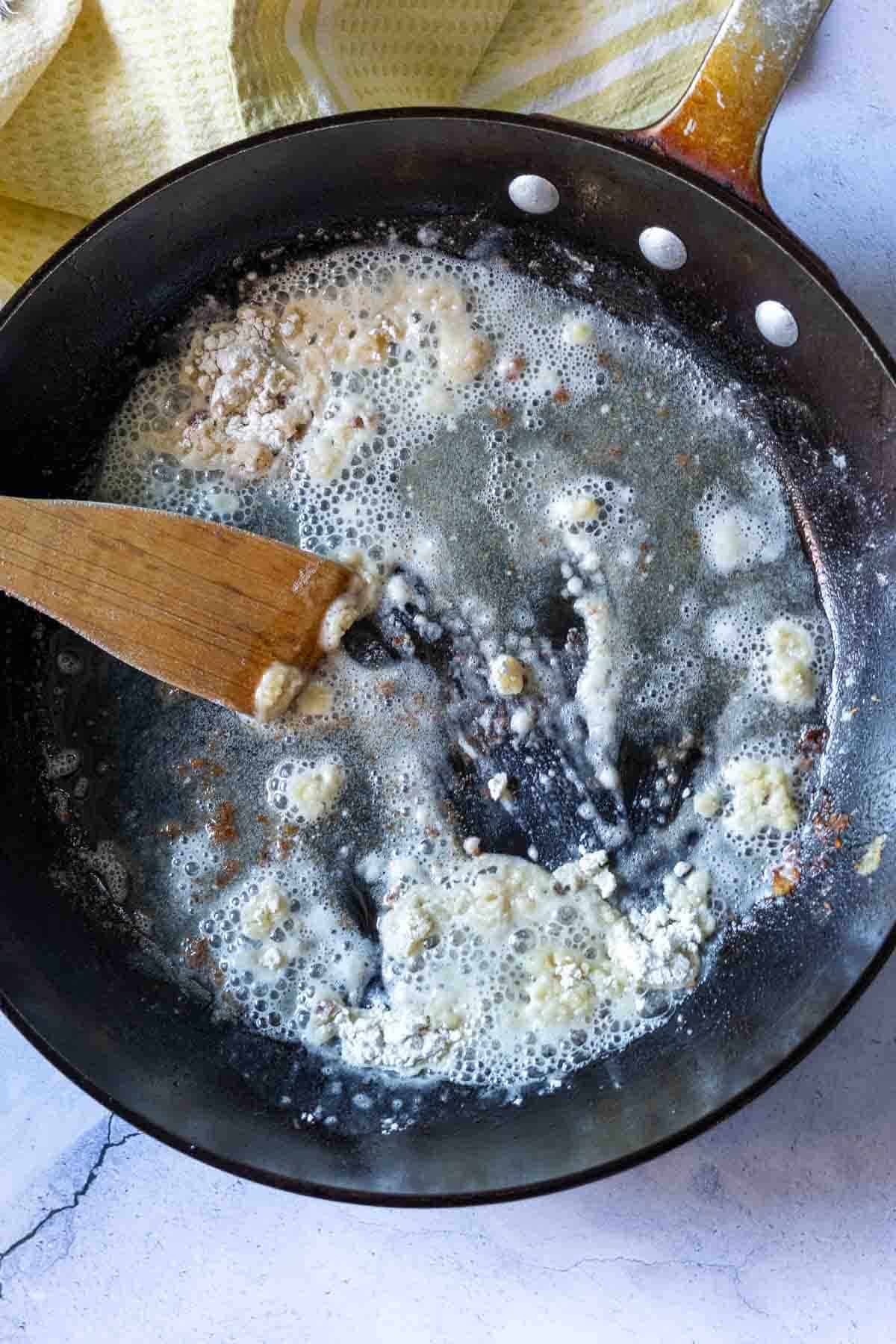 Stirring flour to with oil to make fried chicken gravy.