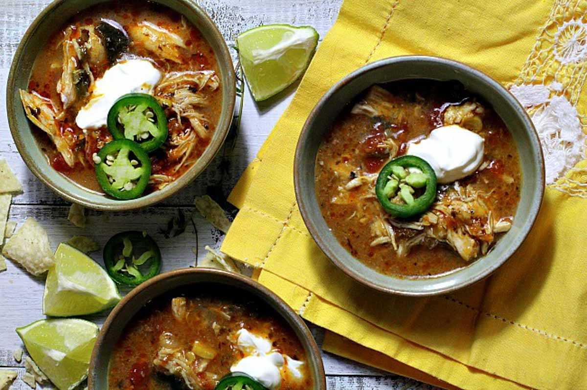 3 bowls of Mexican Chicken tortilla soup topped with sour cream and jalapeno slices