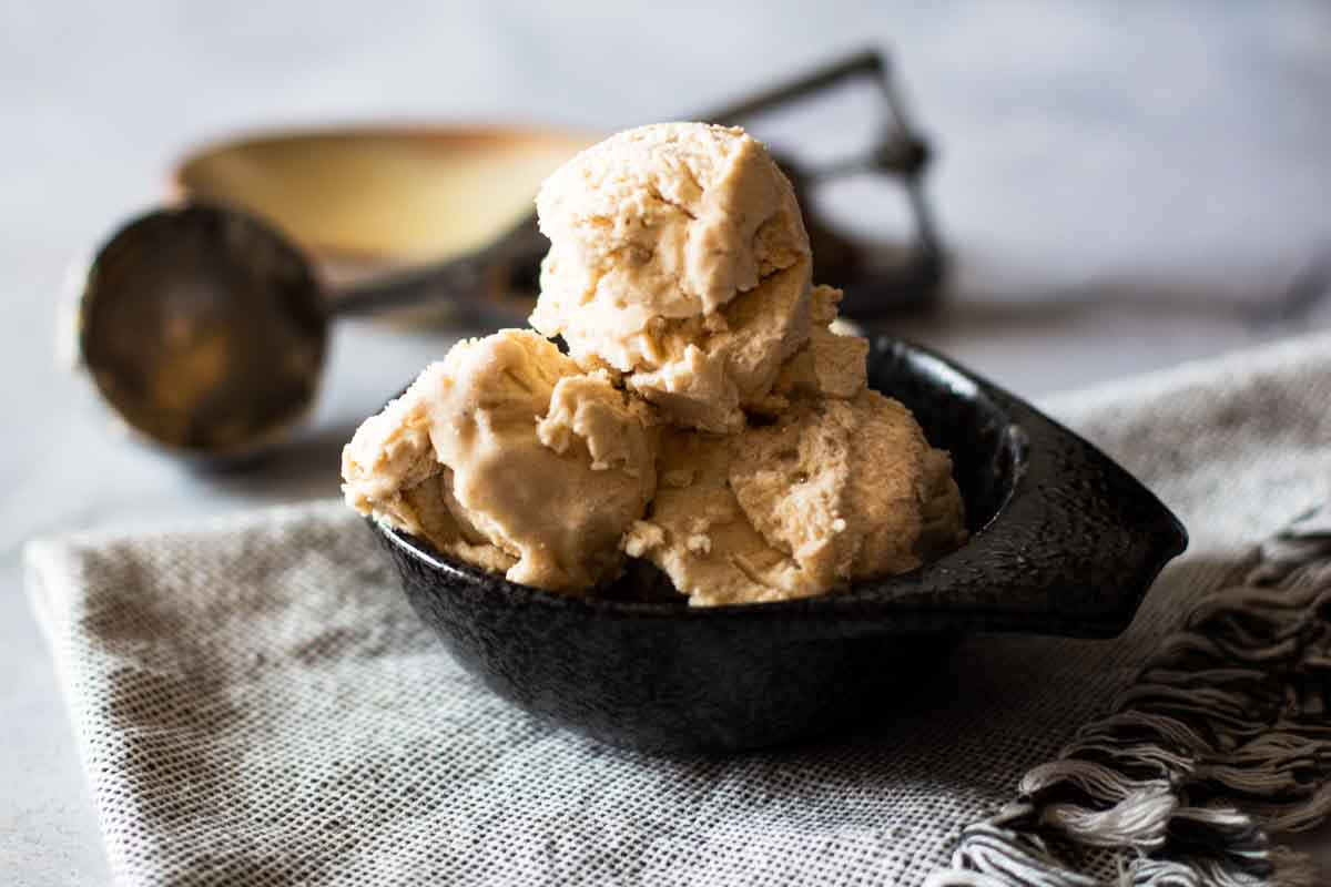Scoops of homemade banana ice cream in a black bowl.