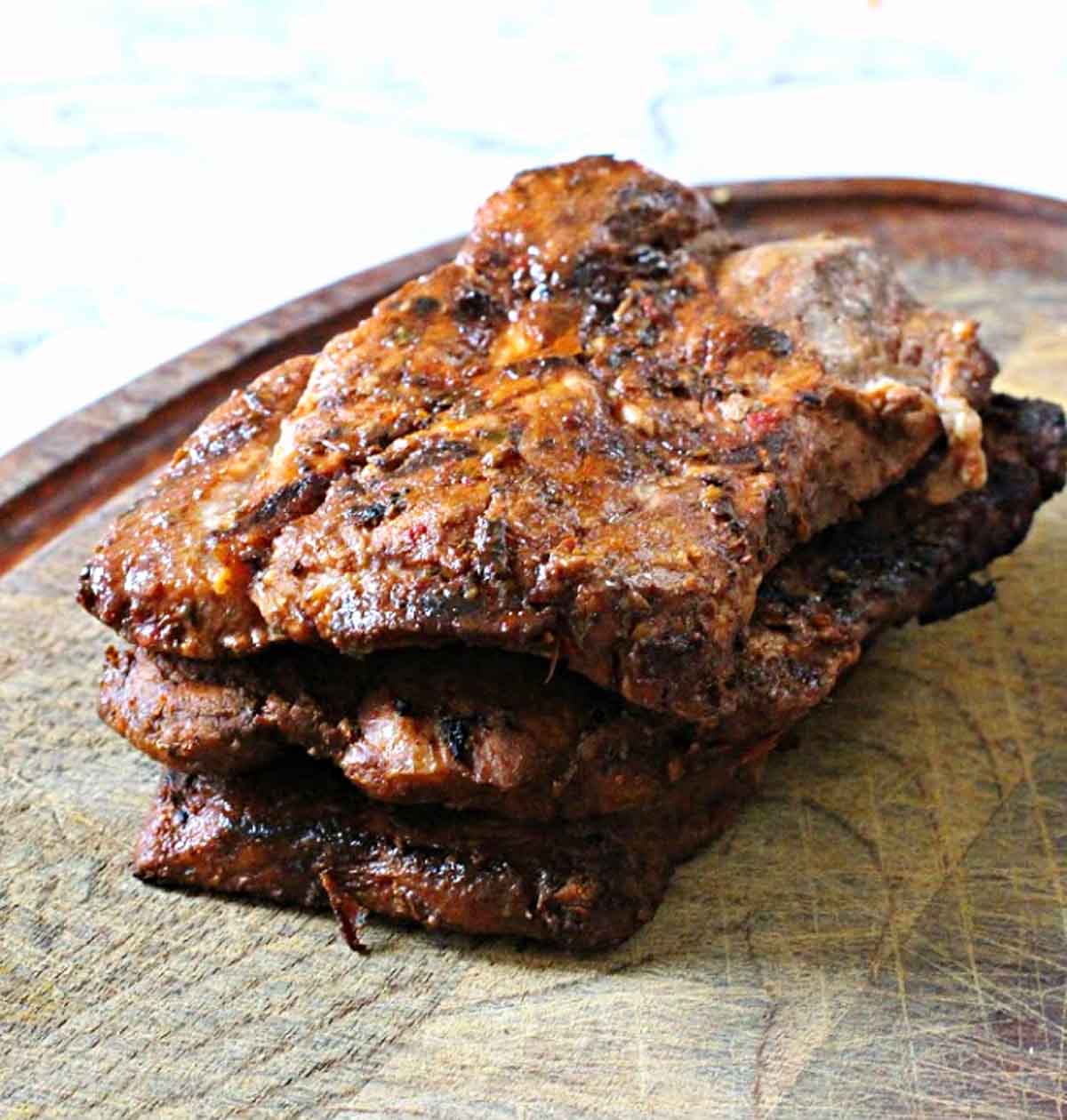 Pork steaks on a cutting board ready to slice for tacos al pastor