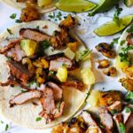 Pork tacos al pastor with pineapple lime wedges on corn tortillas