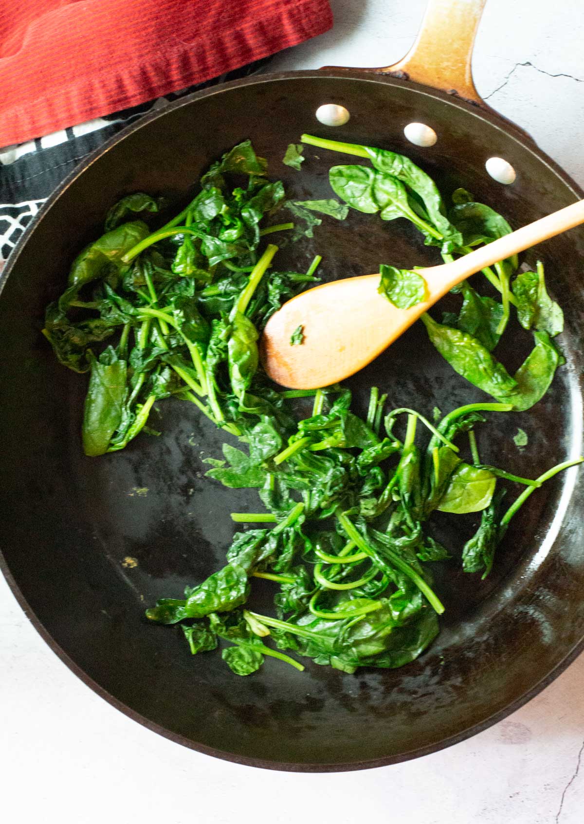 Cooking spinach to make Stuffed Italian Peppers