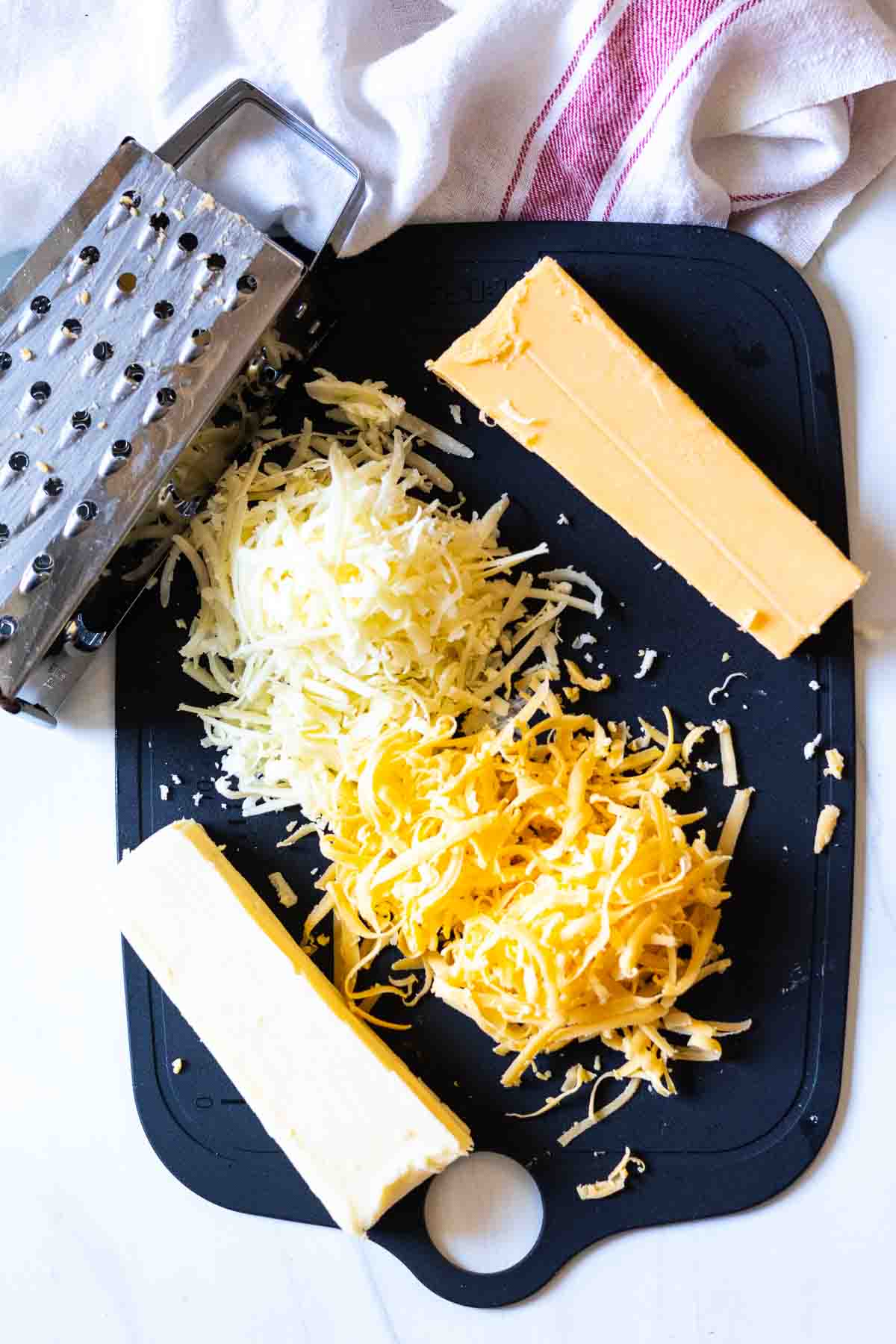 Grating cheese to make spicy pimento cheese spread.