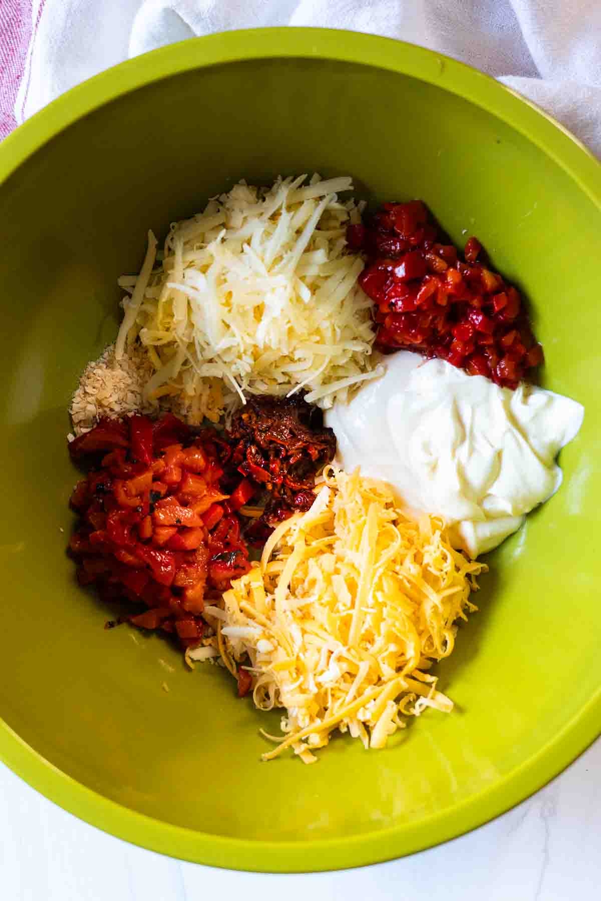 Adding all ingredients to a bowl to make spicy pimento cheese spread.