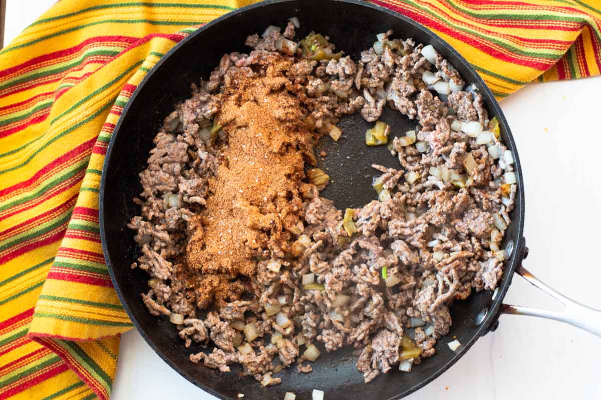 Adding taco seasoning to browned ground beef.