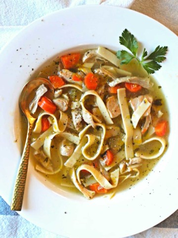 Hearty Chicken Noodle Soup in a white bowl garnished with parsley