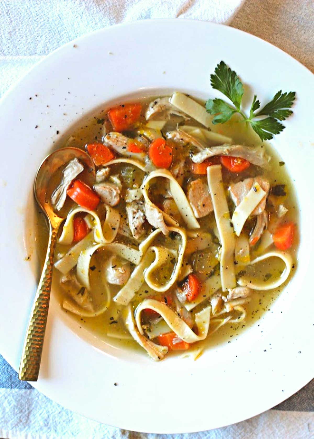 Hearty Chicken Noodle Soup in a white bowl garnished with parsley