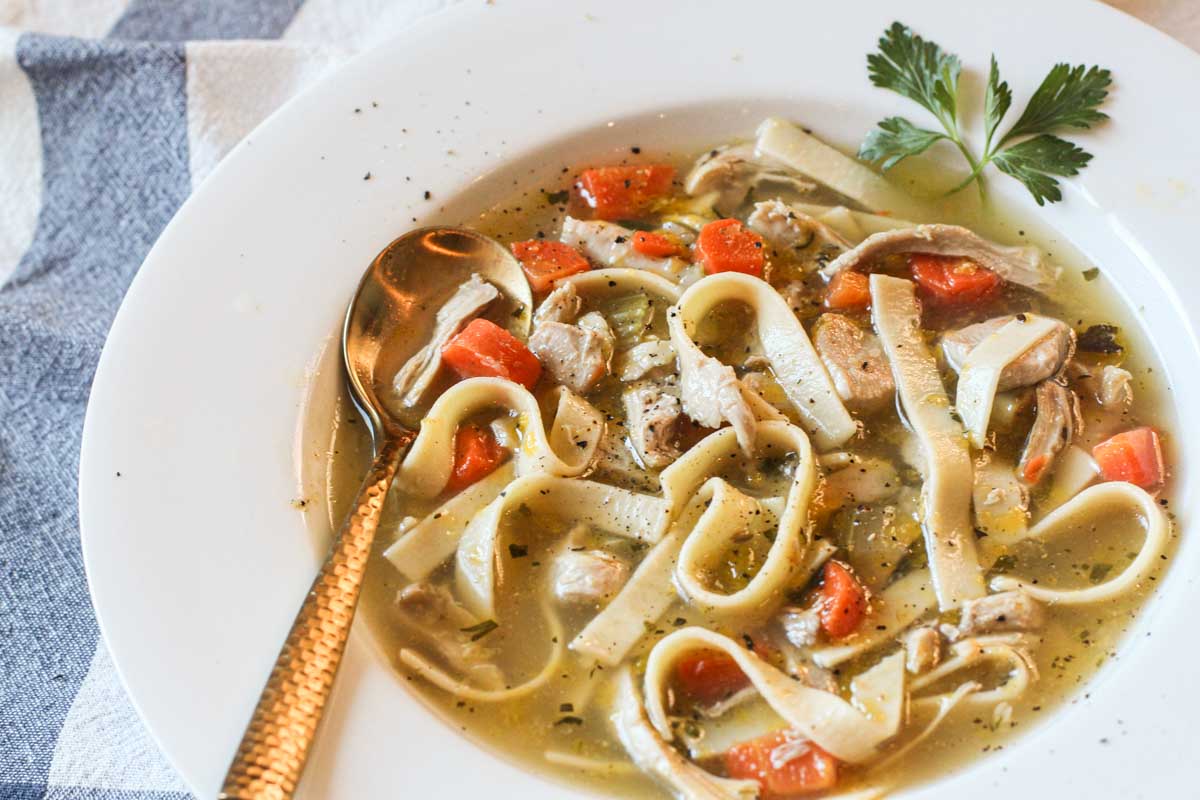 homemade chicken noodle soup from scratch in a white soup bowl