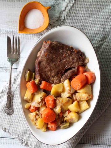Old fashioned pot roast on a platter with potatoes and carrots.