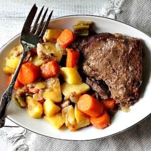 Pot roast dinner with potatoes, carrots and gravy.