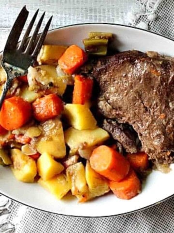 Pot roast dinner with potatoes, carrots and gravy.