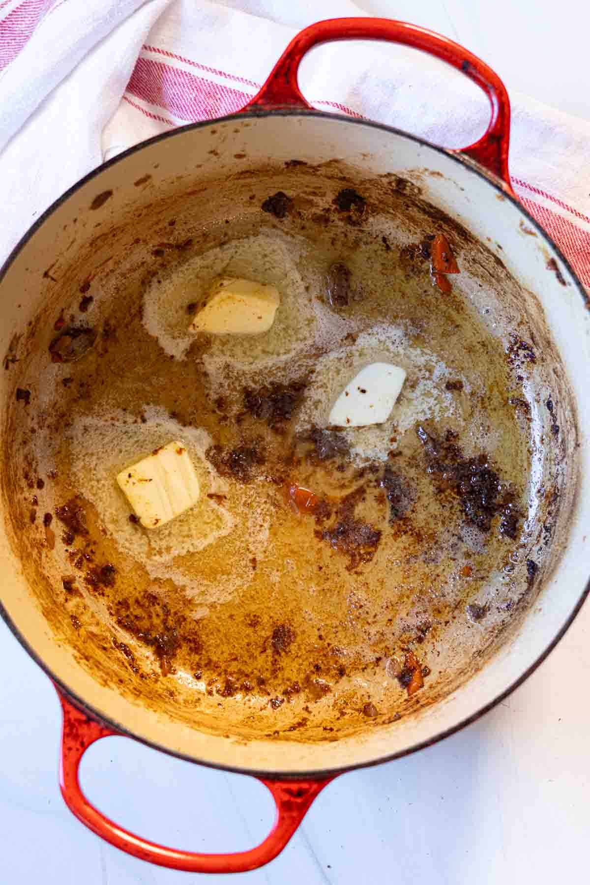 Adding butter to pan to make roast beef gravy.