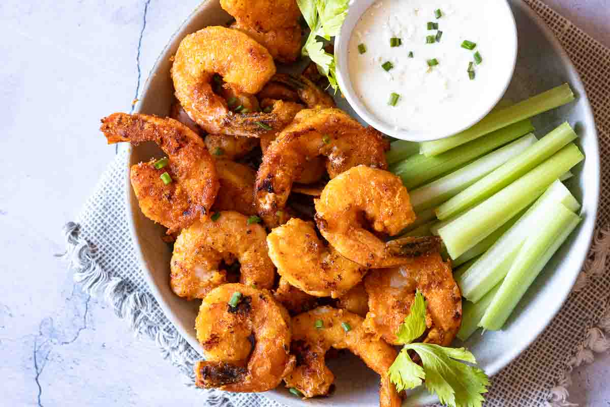 Buffalo shrimp appetizer with celery and blue cheese dressing.