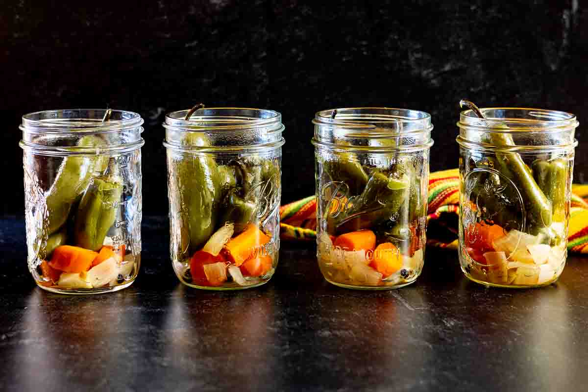 Cooked jalapeno peppers, carrots and onions in canning jars.