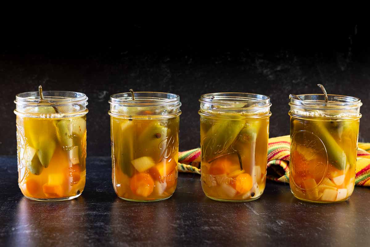 Adding liquid to vegetables in canning jars to make pickled jalapenos.