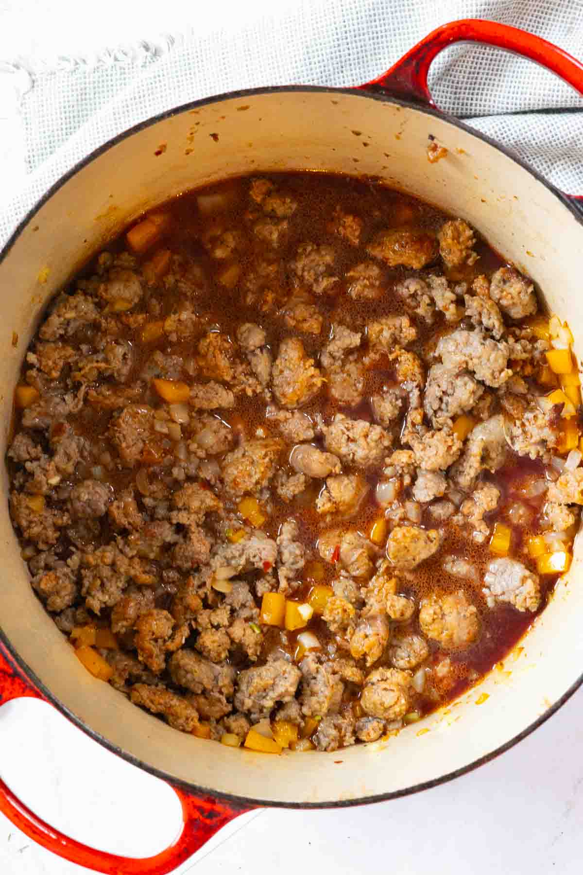 Step 4: Adding beef broth and red wine to sausage and vegetables to make Italian sausage soup.