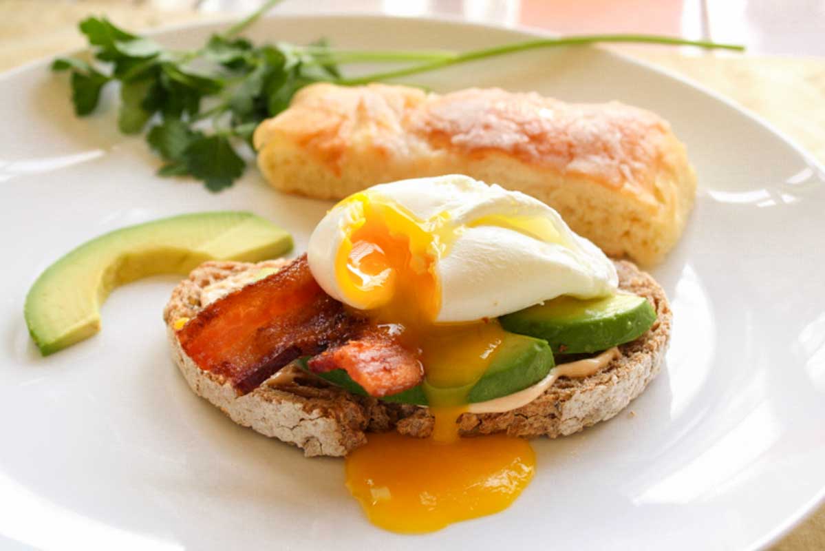 Rustic bread topped with avocado, bacon and a poached egg. 