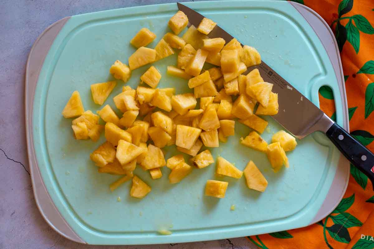 Chopped fresh pineapple on a blue cutting board.