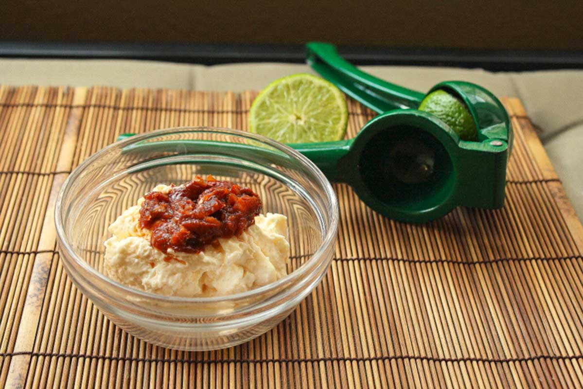 Mayo in a bowl topped with chopped chipotle peppers.