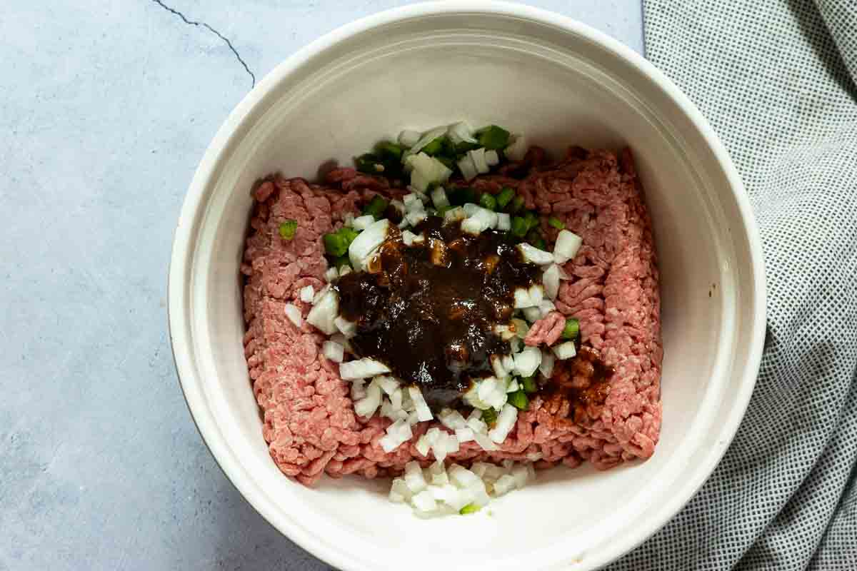 Adding chopped onion, jalapeno pepper and A-1 steak sauce to ground beef to make steak sauce burgers.